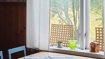 A room with a window, a table with a blue and white striped tablecloth, and a chair.