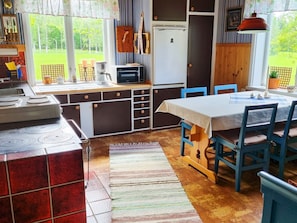 Une cuisine avec un coin repas, un réfrigérateur et une fenêtre donnant sur un espace verdoyant.