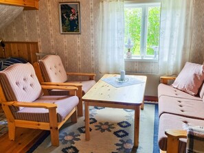 A cozy room with a wooden floor, a patterned rug, a table with a candle, and a window with curtains. - 4 Person Holiday Home in Jarvso (Jarvso)
