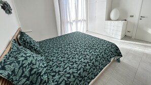 A bedroom with a bed, a wardrobe, and a desk. - Lara's Apartment Mare (Lido di  Camaiore)