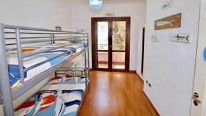 A room with bunk beds, a wooden floor, a door leading outside, and wall-mounted artwork. - Marquis-Taormina holiday home (Taormina)