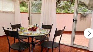 A dining area with a round table, four chairs, and a glass door leading to a garden. - Marquis-Taormina holiday home (Taormina)