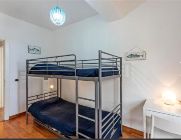 A bunk bed room with a desk and a hanging light fixture.