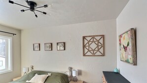 A bedroom with a bed, bedside tables, a dresser, a ceiling fan, and wall decorations.