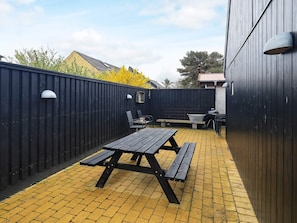 A patio area with a picnic table and chairs, a barbecue grill, and a fenced enclosure. - 4 Star Holiday Home in Skagen (Skagen)
