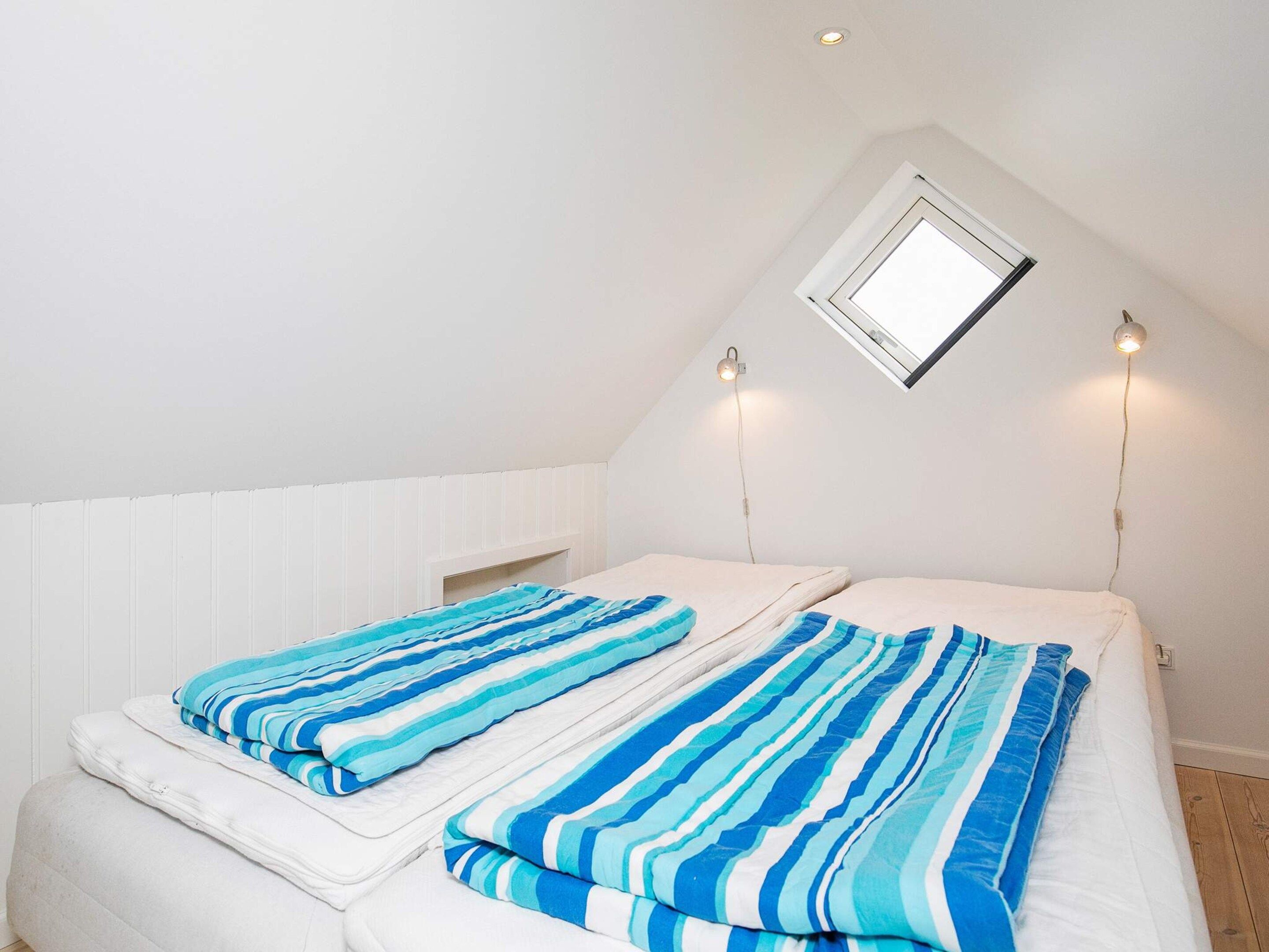 Ein Schlafzimmer mit zwei Betten, einem Oberlicht und zwei Wandleuchten.