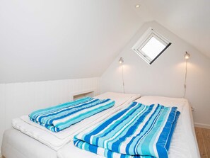 A bedroom with two beds, a skylight, and two wall-mounted lights.