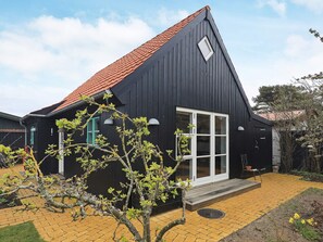 A black building with a red roof, a large window, and a small porch.