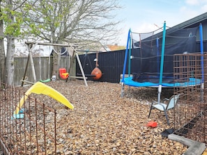 A backyard with a trampoline, swing set, and a yellow play structure. - 4 Star Holiday Home in Skagen (Skagen)
