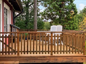 A wooden deck with a railing, a white sign, and trees in the background. - 4 Person Holiday Home in Holsljunga (Holsljunga)