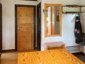 A room with a wooden door, a mirror, a small table, and a coat rack with a jacket. - 4 Person Holiday Home in Holsljunga (Holsljunga)