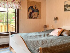 Un dormitorio con una cama, una ventana con vistas, una lámpara de pared y un cuadro.