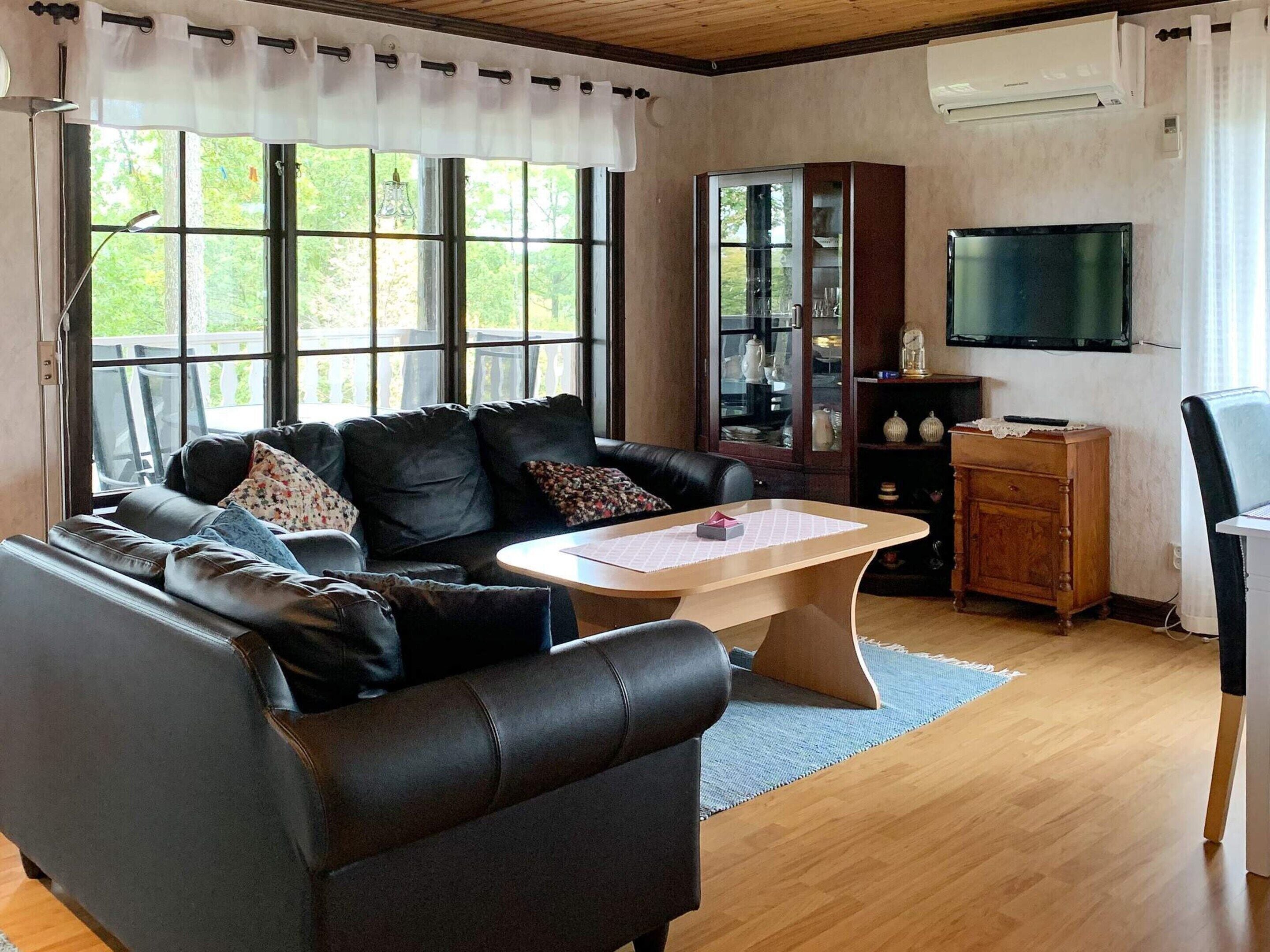 Un salon avec un canapé en cuir, une table basse en bois, un téléviseur et un meuble.