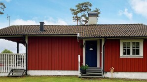 Un edificio rosso con tetto in tegole, una porta blu e un piccolo portico con gradini.