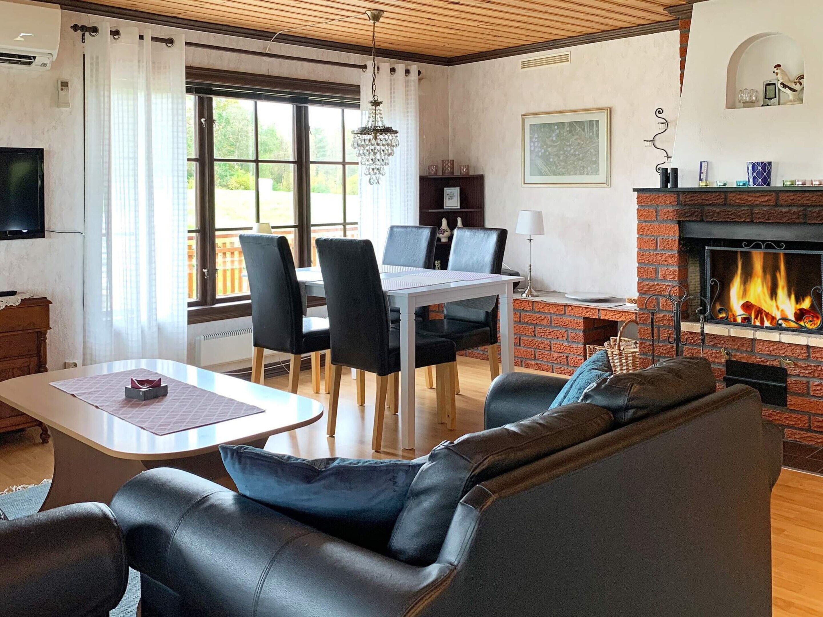 A living room with a fireplace, a dining area with chairs, a sofa, and a television.