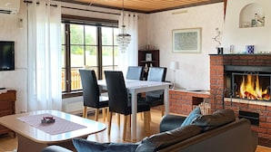 Un salon avec une cheminée, un coin repas avec des chaises, un canapé et un téléviseur.