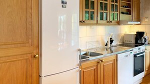 Une cuisine avec des meubles de rangement en bois, un réfrigérateur blanc, un lave-vaisselle et une cuisinière.