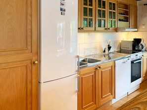 Une cuisine avec des meubles de rangement en bois, un réfrigérateur blanc, un lave-vaisselle et une cuisinière.