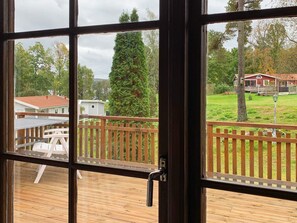 A wooden deck with a view of a fenced yard and a red building.
