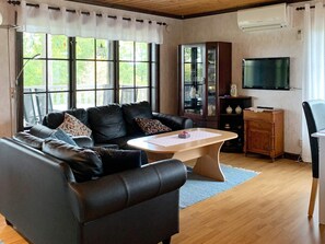 A living room with a leather sofa, a wooden coffee table, a television, and a cabinet. - 4 Person Holiday Home in Holsljunga (Holsljunga)