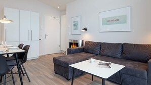 A modern living room with a grey sofa, a white coffee table, and a dining area with a table and chairs. - 5 Star Holiday Home in Wendtorf (Wendtorf)