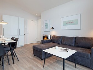 A modern living room with a grey sofa, a white coffee table, and a dining area with a table and chairs. - 5 Star Holiday Home in Wendtorf (Wendtorf)