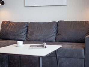 A modern living area with a grey sofa, a white coffee table, and a framed picture on the wall.