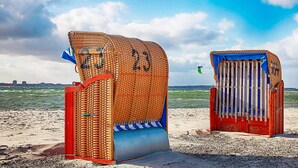 Two beach huts with numbers 23 and 24, a sandy beach, and a view of the sea. - 5 Star Holiday Home in Wendtorf (Wendtorf)