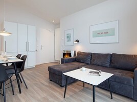 Una sala moderna con un sofá gris, una mesa de centro blanca y un comedor con mesa y sillas.