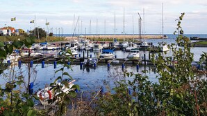 A marina with multiple boats docked, a sandy beach in the background, and a clear sky. - 4 Star Holiday Home in Smygehamn (Trelleborg)
