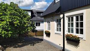 A two-story house with a gravel driveway and a large tree in the foreground. - 4 Star Holiday Home in Smygehamn (Trelleborg)