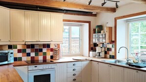 A kitchen with wooden cabinets, a colorful backsplash, a built-in oven, and a window with a view. - 4 Star Holiday Home in Smygehamn (Trelleborg)