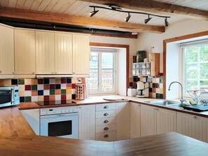 A kitchen with wooden cabinets, a colorful backsplash, a built-in oven, and a window with a view. - 4 Star Holiday Home in Smygehamn (Trelleborg)