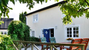 A wooden deck with outdoor furniture, a white building with a blue door, and a garden area. - 4 Star Holiday Home in Smygehamn (Trelleborg)