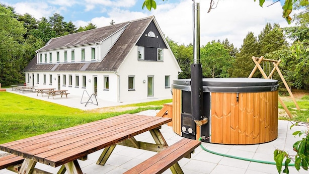 Ett modernt hus med en bubbelpool och picknickbord på gården.