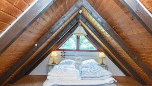 A cozy attic bedroom with a sloped ceiling, a bed with white bedding, two bedside lamps, and a window with a view of trees. - 6 Person Holiday Home in Toftlund (Toftlund)