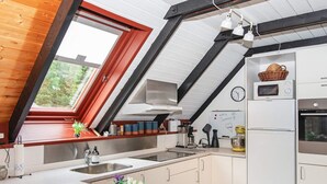 A modern kitchen with a sloped ceiling, a built-in oven, and a microwave on the countertop. - 6 Person Holiday Home in Toftlund (Toftlund)