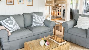 A modern living room with a grey sofa, striped pillows, and a coffee table with decorative items. - 6 Person Holiday Home in Lokken (Lokken)