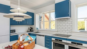 Una cucina moderna con mobili blu, piani di lavoro bianchi e forno integrato.
