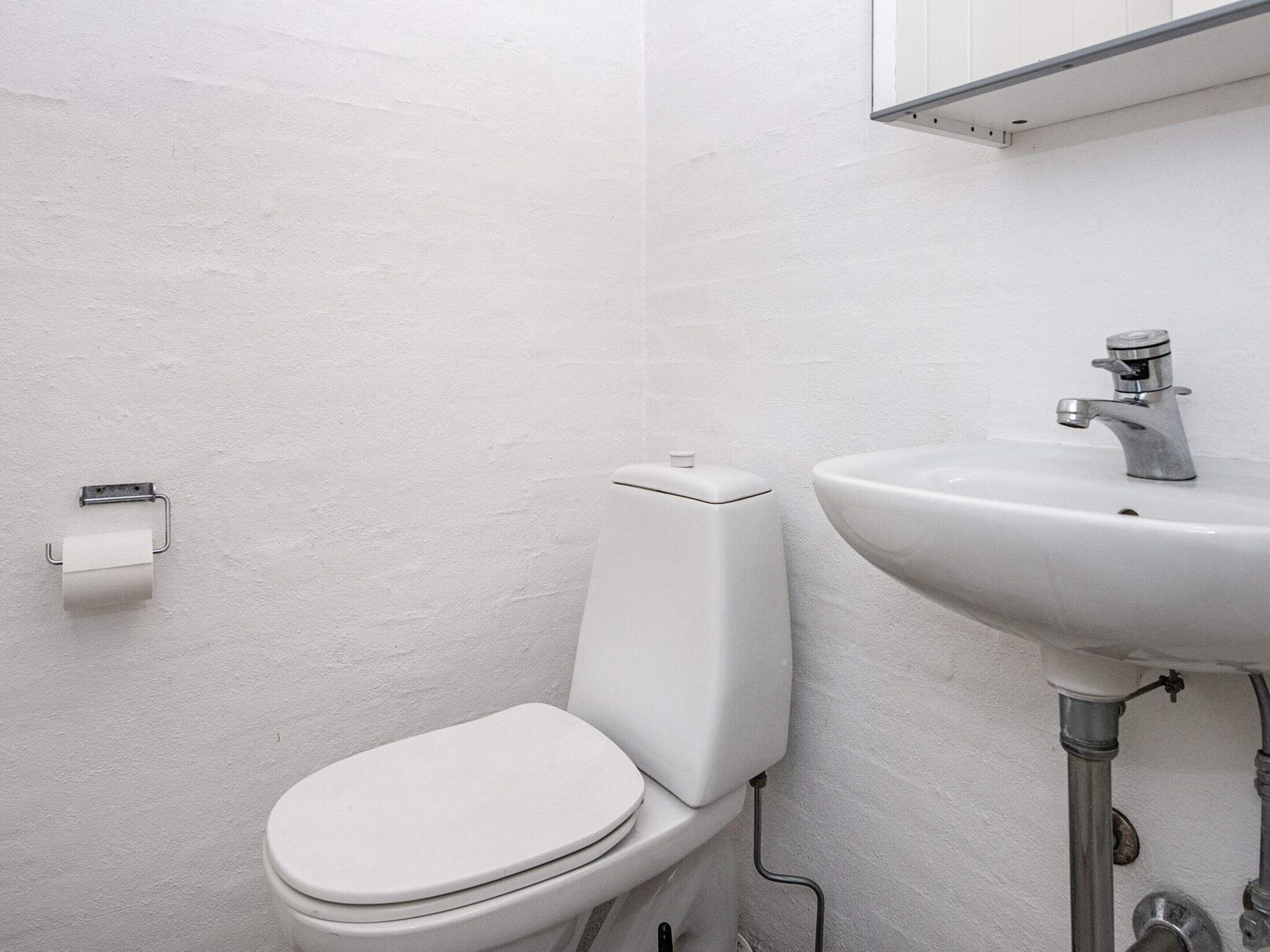 Ein Badezimmer mit Toilette, Waschbecken und Toilettenpapierhalter.