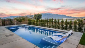 Una piscina con vistas a montañas y al atardecer.
