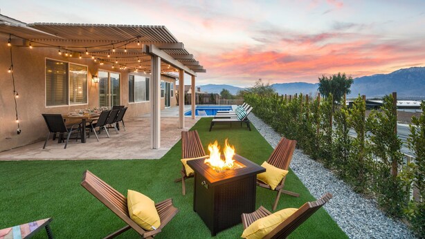 Un patio con una fogata, asientos al aire libre y una piscina.