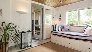 A cozy room with a bed, a window with a view, a potted plant, and a door leading to another room. - 6 Person Holiday Home in Blavand (Blavand)