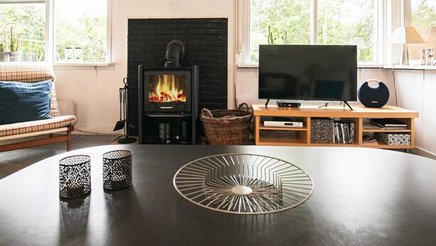 A living room with a fireplace, a television, and a table with decorative items. - 6 Person Holiday Home in Blavand (Blavand)