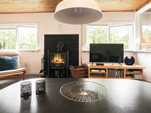 A living room with a fireplace, a television, and a table with decorative items. - 6 Person Holiday Home in Blavand (Blavand)