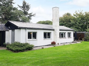 A white building with a chimney, a small porch, and a grassy yard. - 6 Person Holiday Home in Blavand (Blavand)
