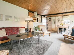A living room with a sofa, a coffee table, and a dining area with chairs and a table. - 6 Person Holiday Home in Blavand (Blavand)