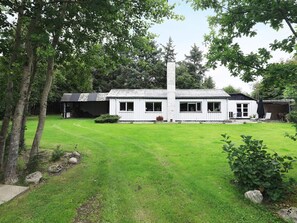 A white building with a tiled roof, a tall chimney, and a well-maintained lawn. - 6 Person Holiday Home in Blavand (Blavand)
