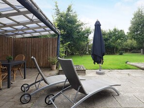 A patio area with a covered seating area, a table with chairs, and a swing set. - 6 Person Holiday Home in Blavand (Blavand)