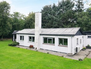 A white building with a chimney, windows, and a grassy yard. - 6 Person Holiday Home in Blavand (Blavand)